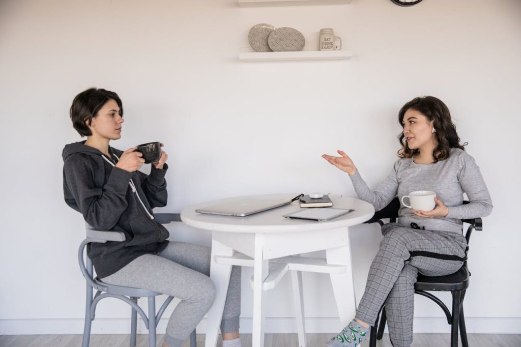 Two women enjoying a casual conversation with coffee in a cozy indoor setting, enhancing connections.